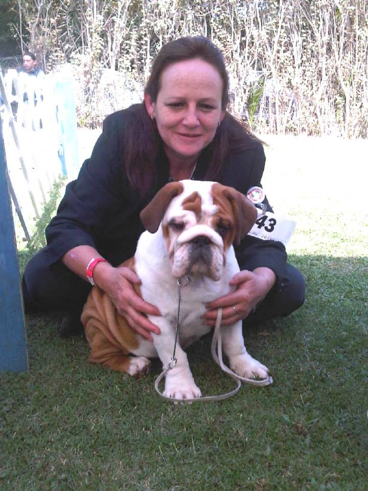 karen vestida formalmente de handler con su numero de participación tomado en su brazo y junto a una cachorra bulldog inglés