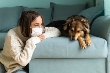 mujer con mascarilla sentada junto a su perro