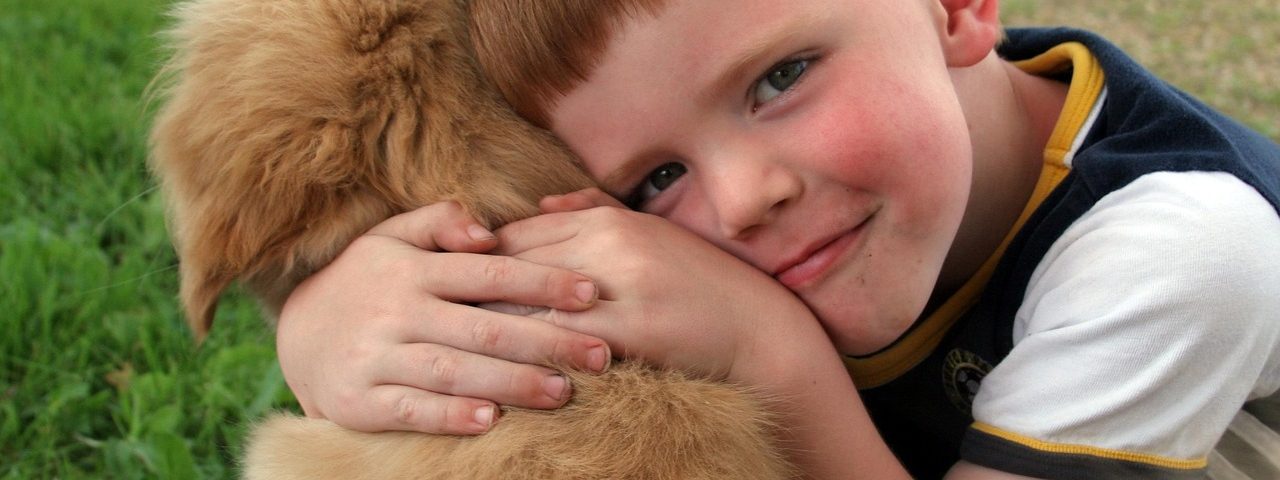 niño abrazando a un cachorro canino