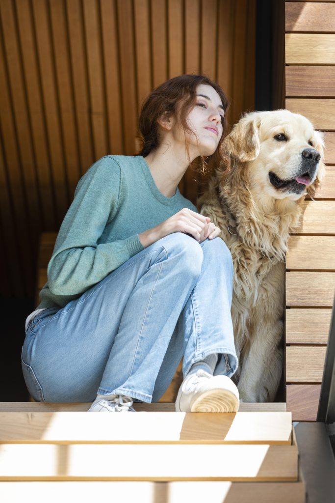 TUTORA SENTADO JUNTO A SU PERRO GOLDEN EN LA ESCALERA A LA ENTRADA DE LA CASA MIRANDO HACIA LA DISTANCIA