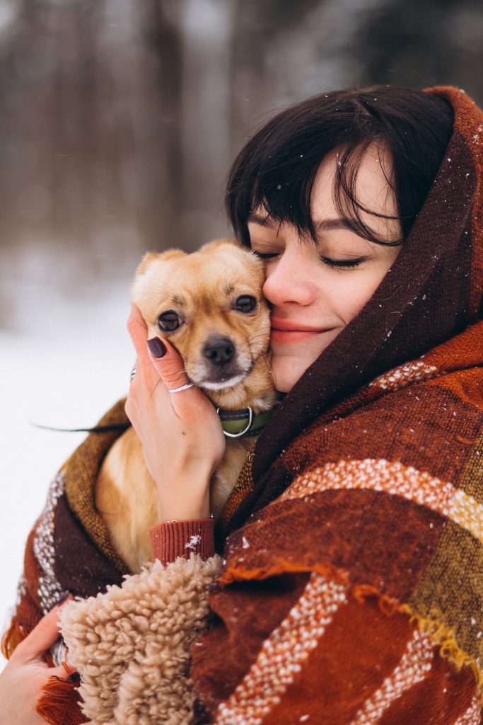 Young woman outside the park with her little dog at winter