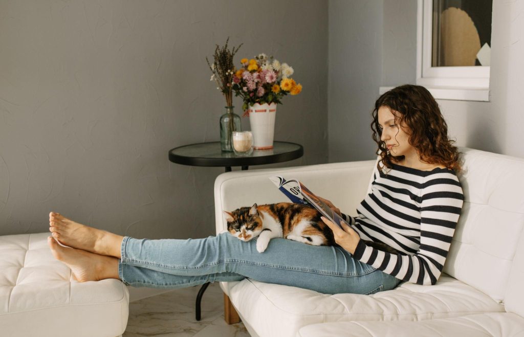 persona tendida o sentada junto a su gato en el sofá